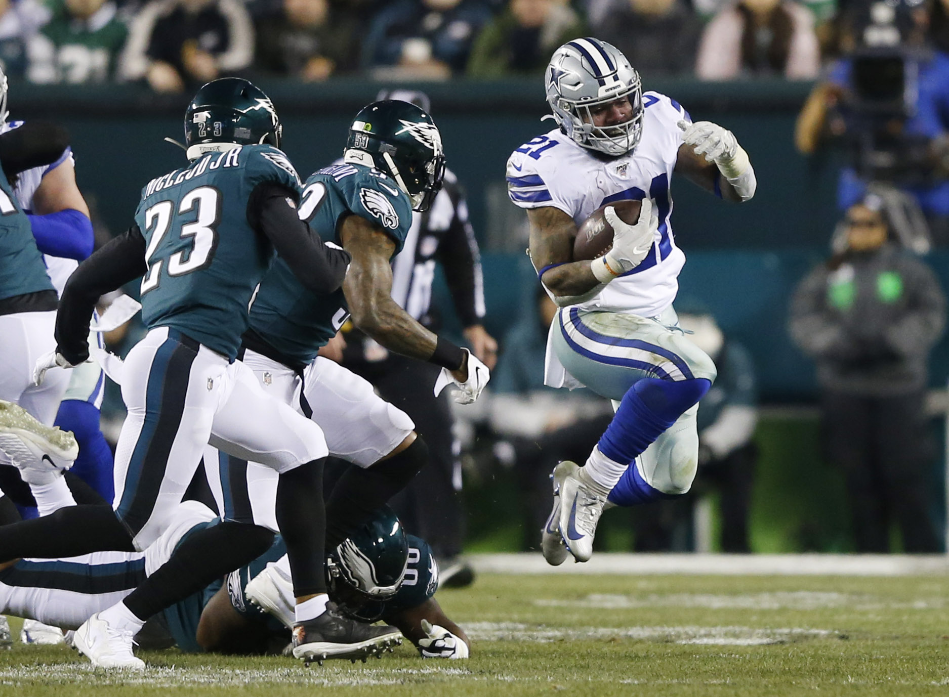 Dallas Cowboys running back Ezekiel Elliott (21) leaps to evade a tackle from Philadelphia...