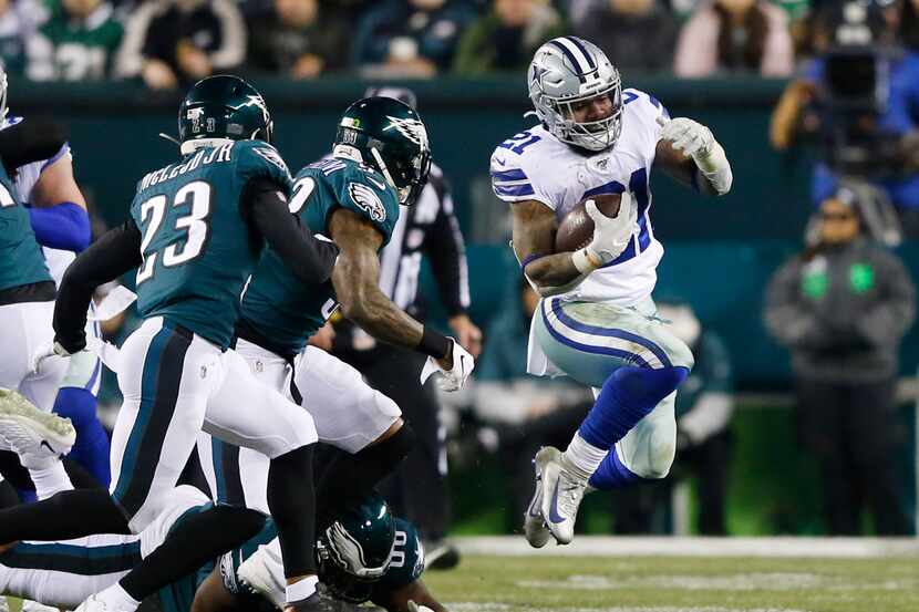 Dallas Cowboys running back Ezekiel Elliott (21) leaps to evade a tackle from Philadelphia...