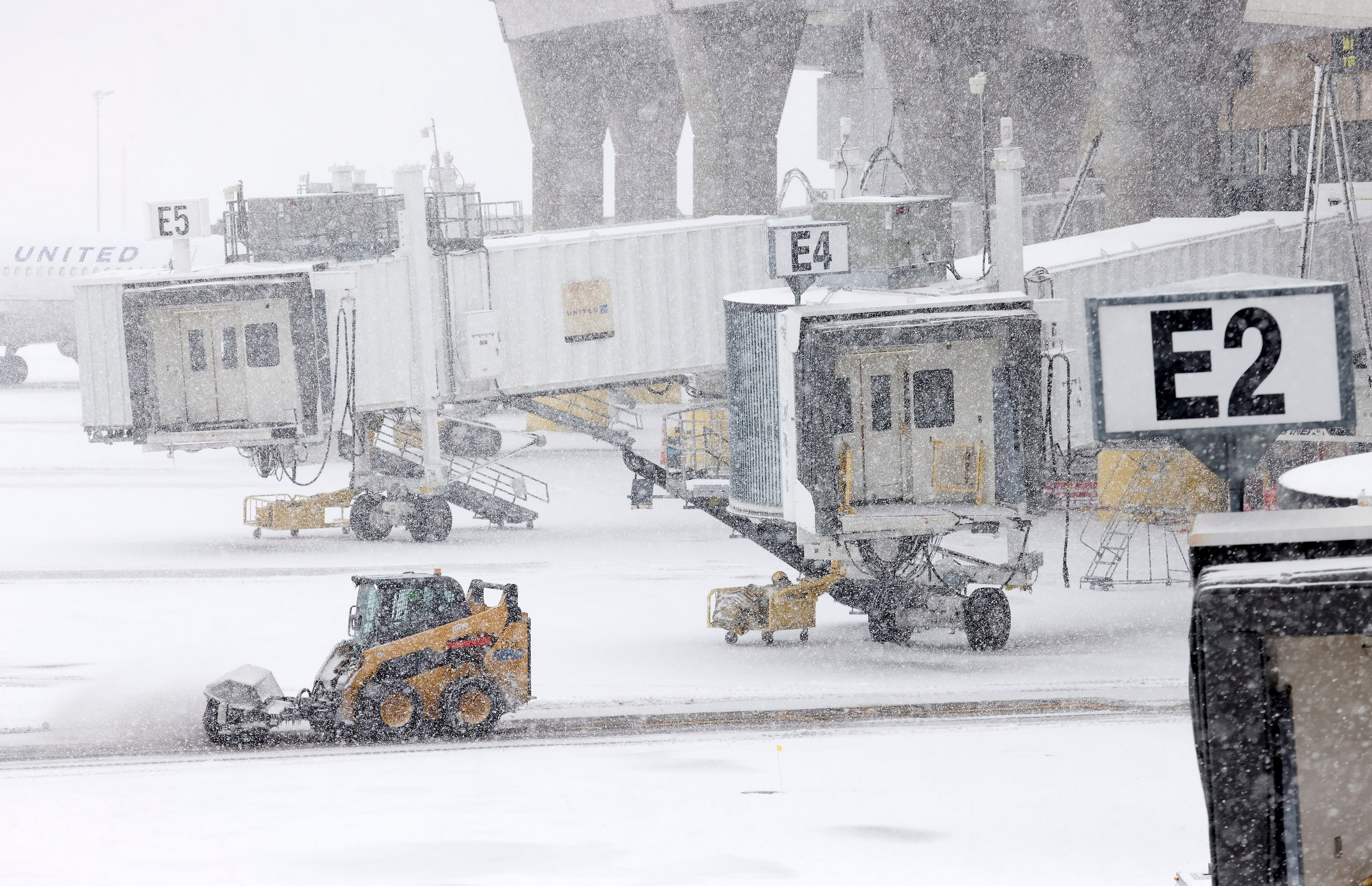 With sleet turning to blowing snow, ground crews clear gate guidance markings at DFW...