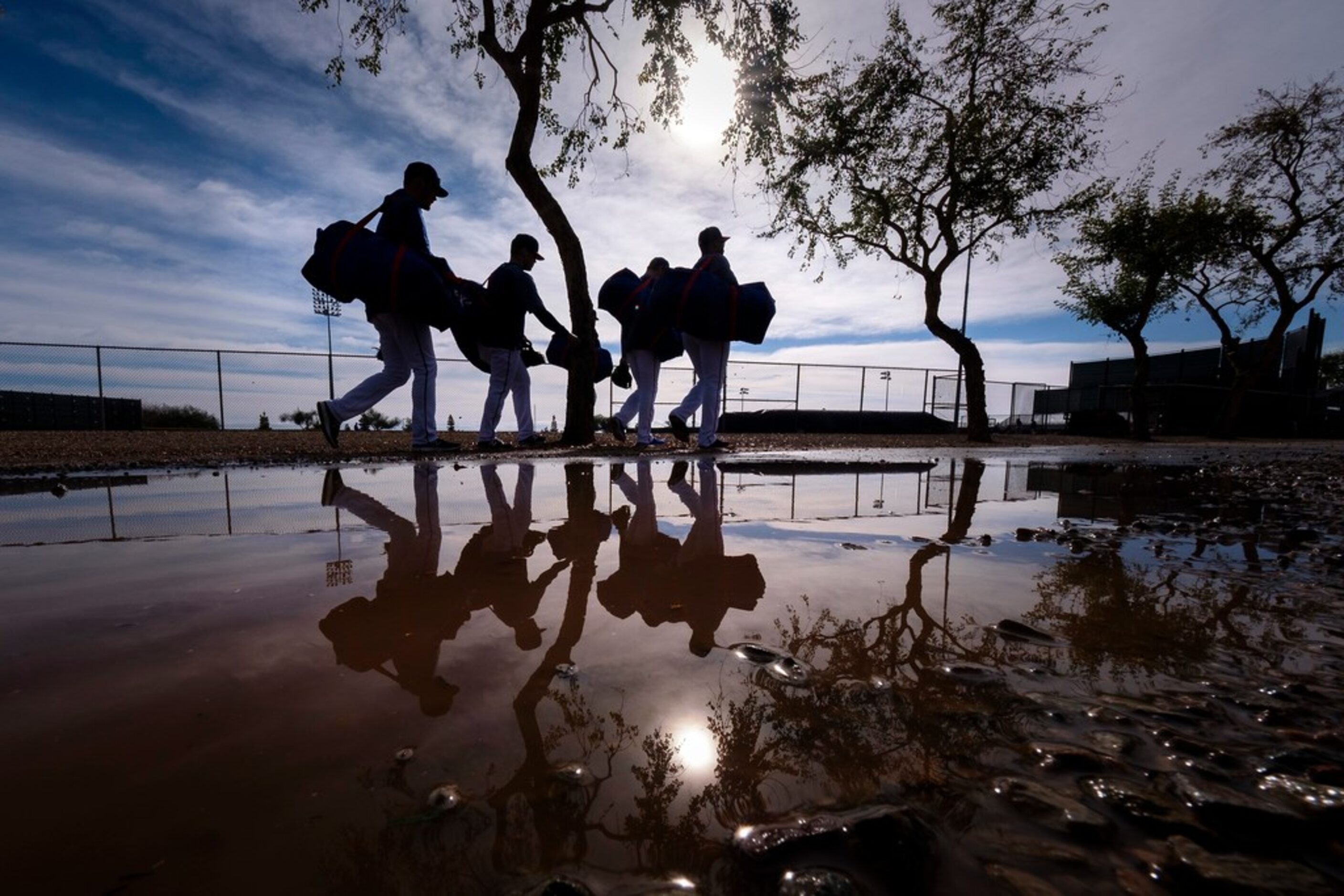 Texas Rangers players dodge puddle left over from the previous day's rains as he heads for...