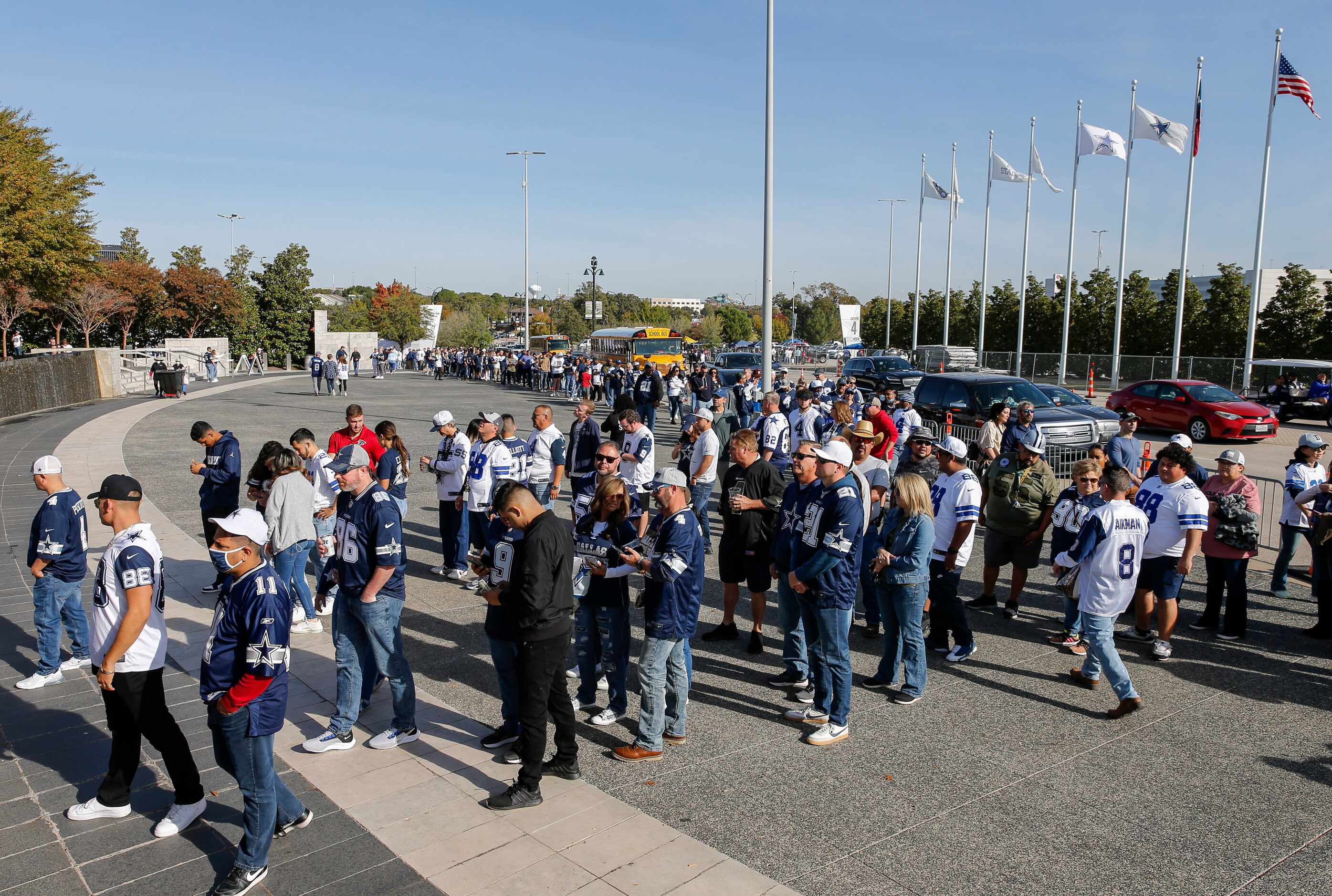 Fans wait in line to enter the stadium before an NFL football game between the Dallas...