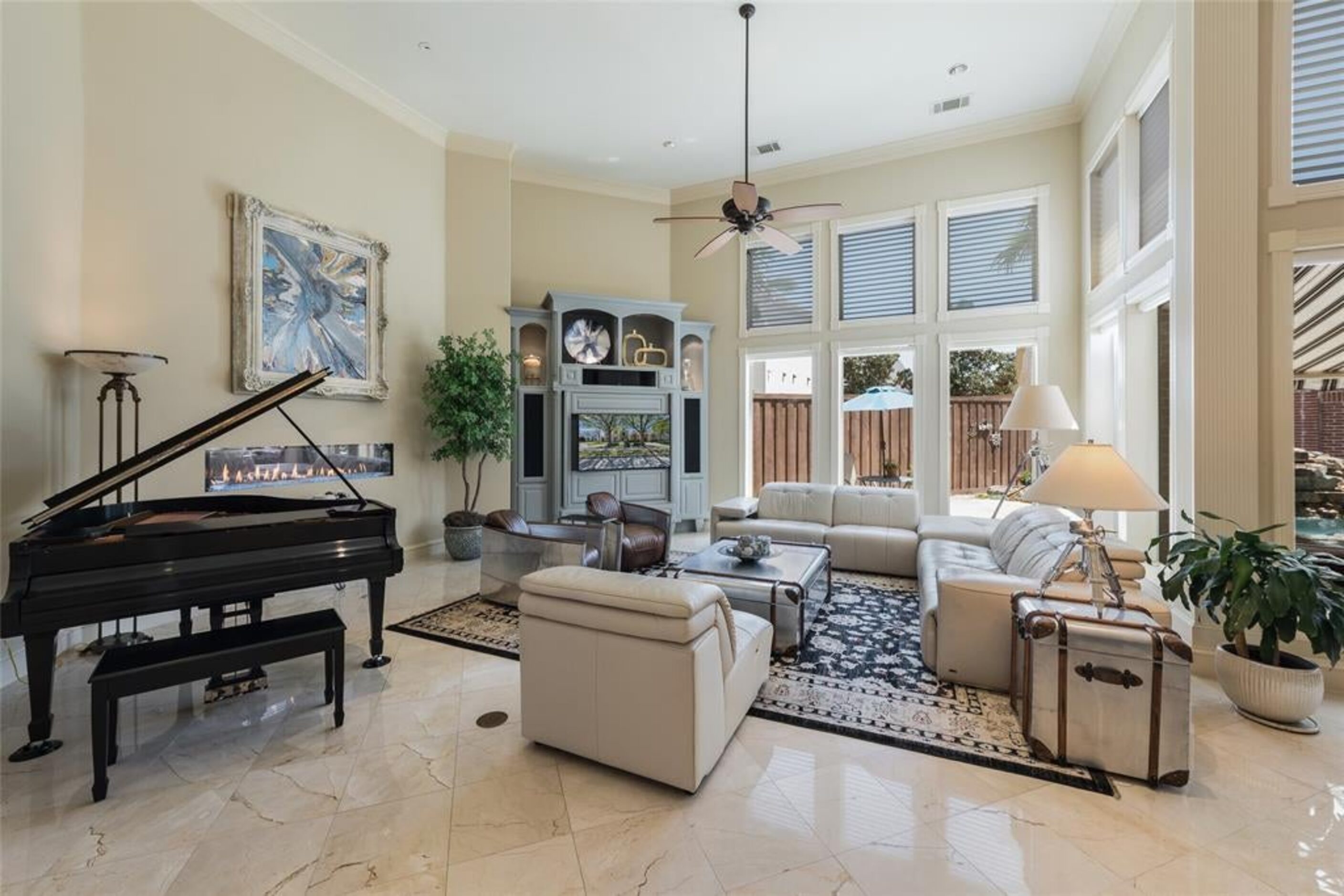 The front room is staged with a piano and offers a look outside toward the pool and patio.