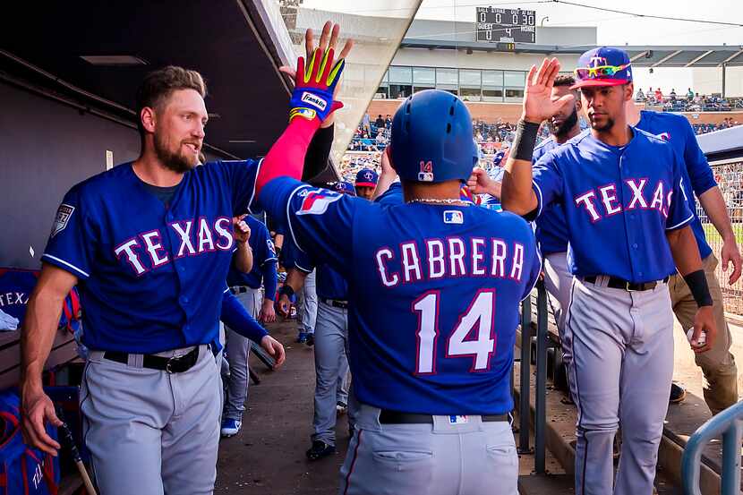 Rangers third baseman Asdrúbal Cabrera gets high-fives from outfielders Hunter Pence (left)...