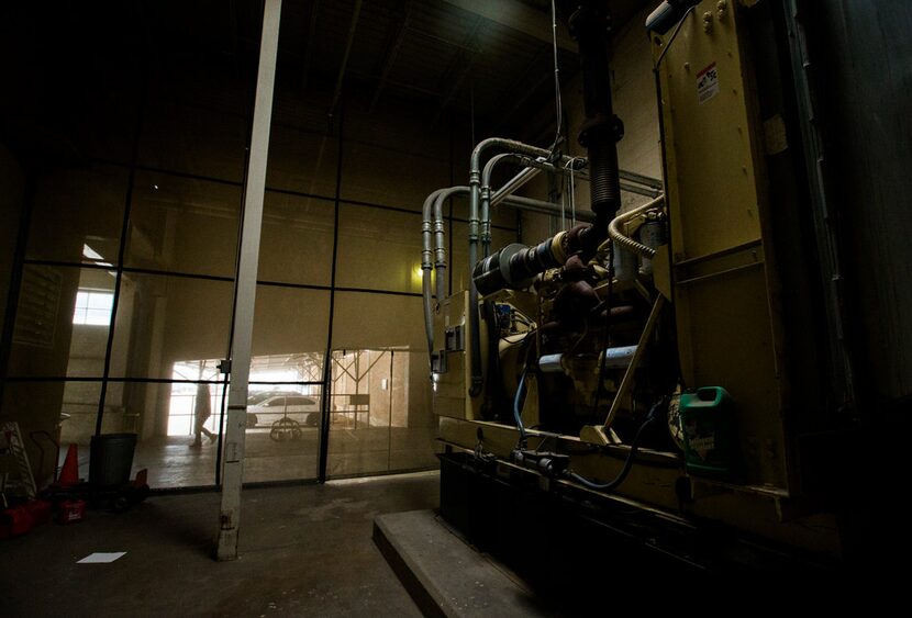 An employee passes large machinery kept hidden by a wall of mesh near the back entrance of...