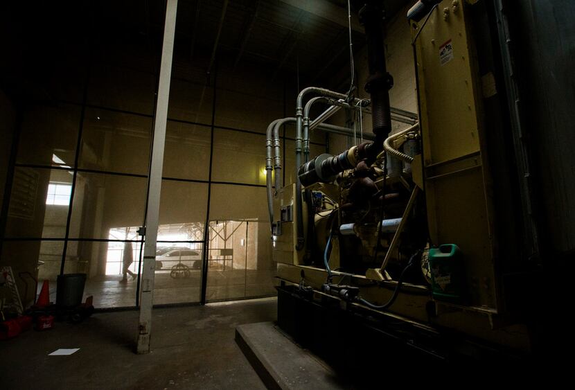 An employee passes large machinery kept hidden by a wall of mesh near the back entrance of...