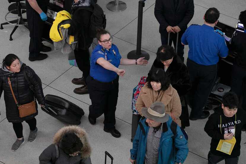 A TSA agent directs passengers through a security checkpoint at New York's John F. Kennedy...
