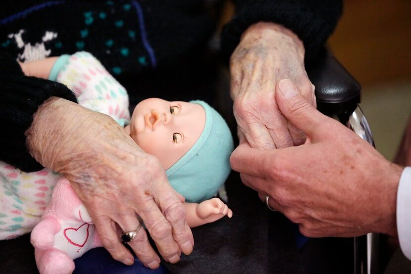 In this 2016 file photo, a son holds his mother's hand at her nursing home. 