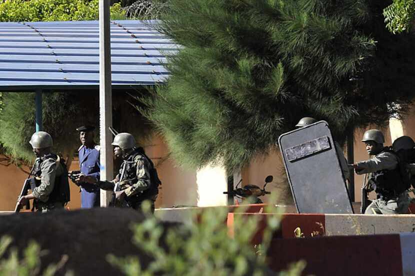 Malian troops take position Friday outside the Radisson Blu hotel in Bamako. Gunmen went on...