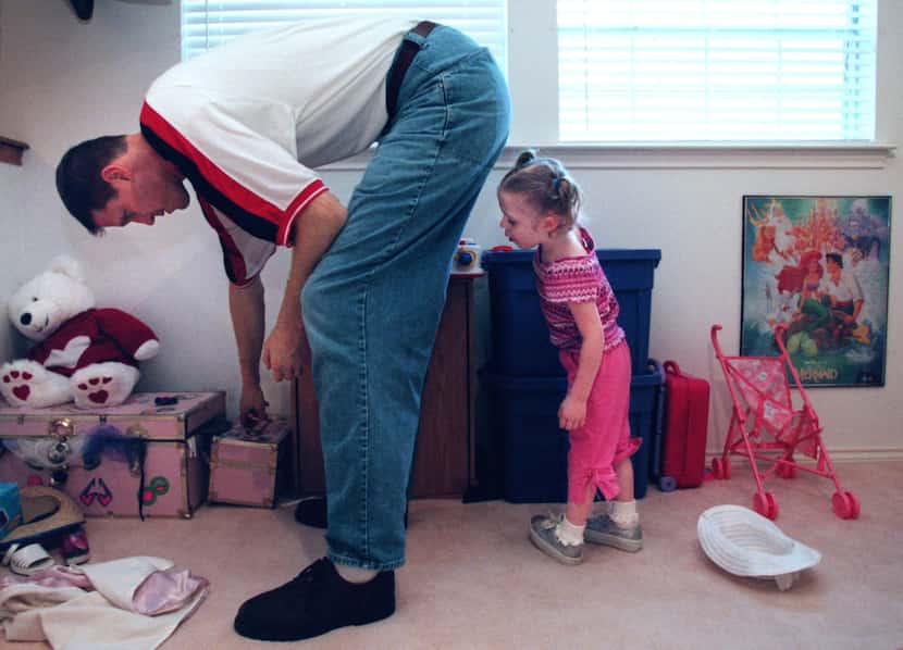 Dallas Mavericks center Shawn Bradley helps his daughter Chelsea, 3, find a toy in the...