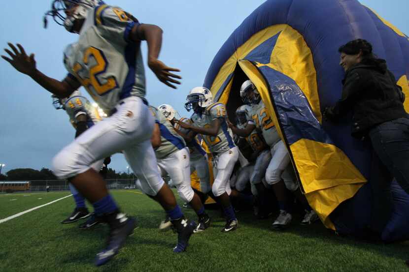 Members of the Samuell Spartans emerge from an inflatable tunnel just prior to the opening...