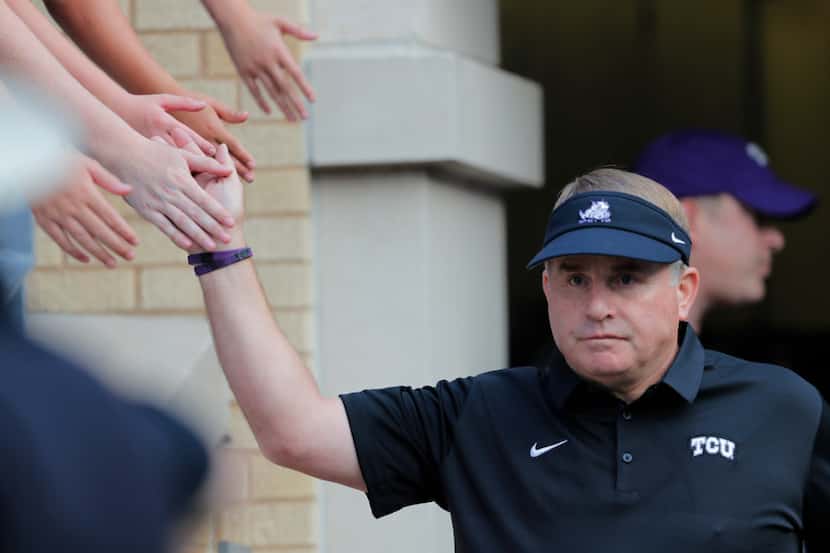 Texas Christian head coach Gary Patterson slaps hands with fans as he walks onto the field...