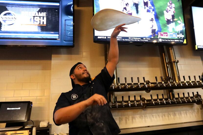 Mitch Rotolo tosses a pizza crust at the bar featuring the beer craft tower during the...