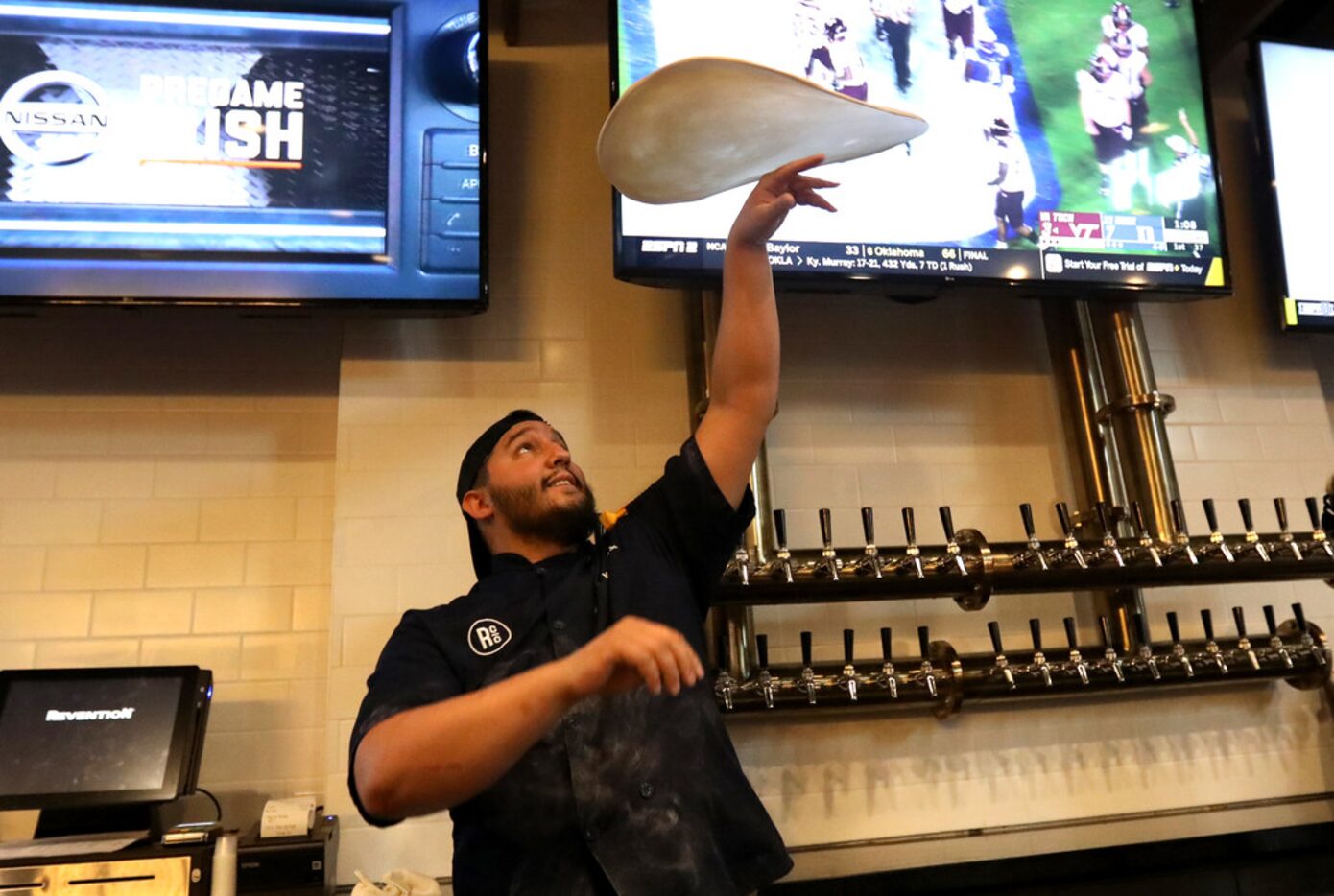 Mitch Rotolo tosses a pizza crust at the bar featuring the beer craft tower during the...