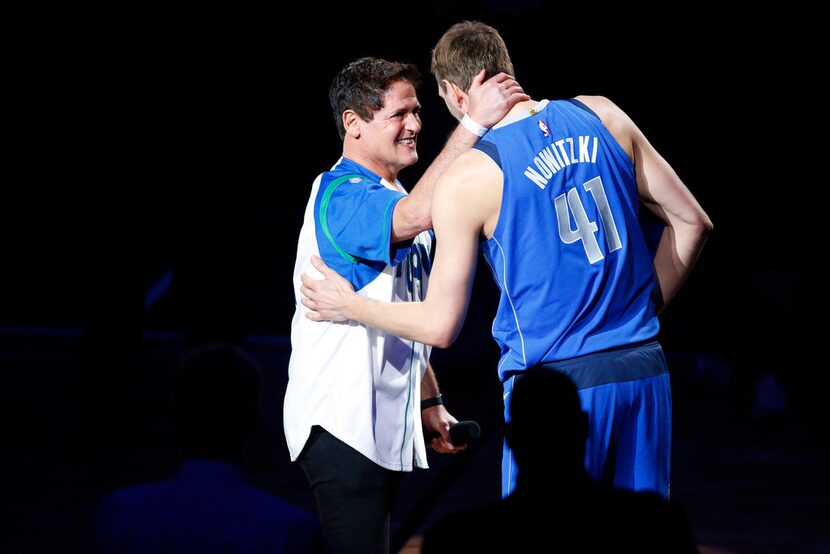 Dallas Mavericks owner Mark Cuban (left) honors forward Dirk Nowitzki (right) during a post...