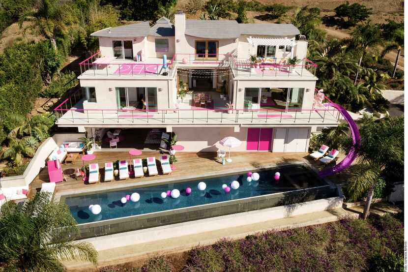 Foto de la mansión de tres pisos Barbie, que es de color blanco y rosa, con una alberca y...