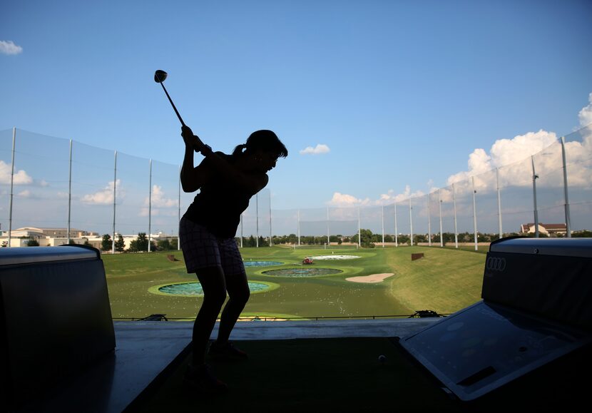 A patron o fTopGolf takes a swing during her company's annual team building event at Topgolf...