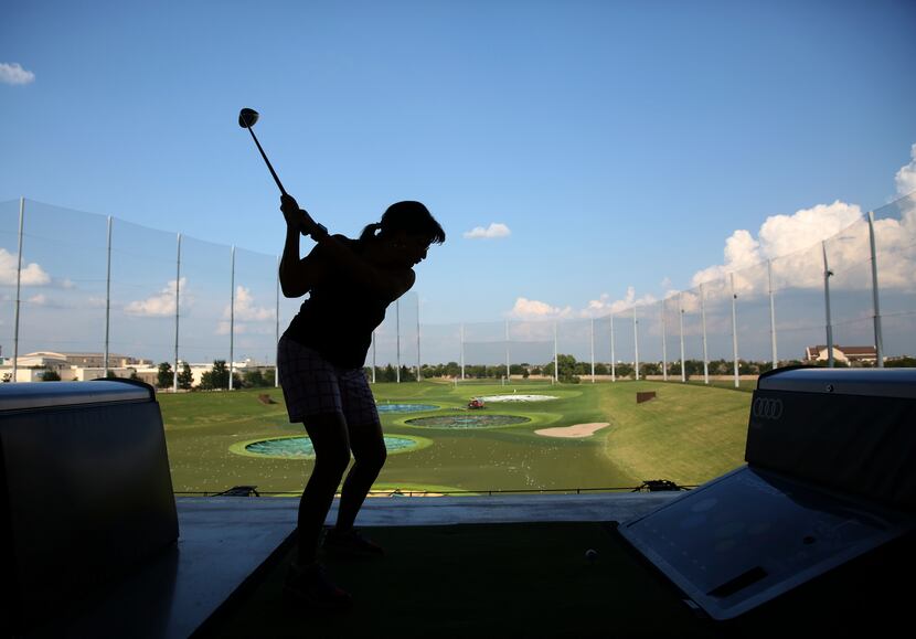 A patron o fTopGolf takes a swing during her company's annual team building event at Topgolf...