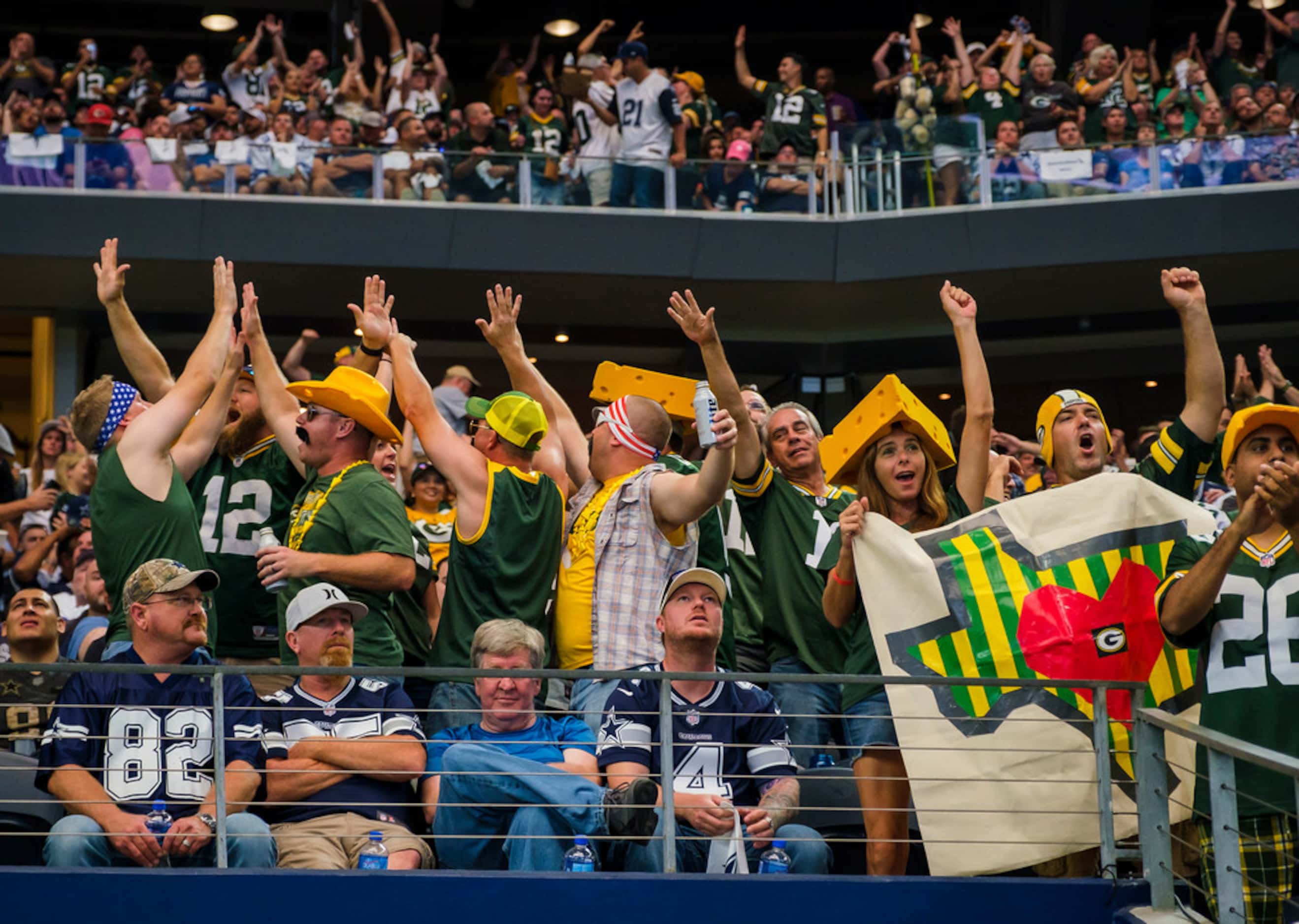 Green Bay Packers fans cheer a Packers touchdown as Dallas Cowboys fans sit in silence...