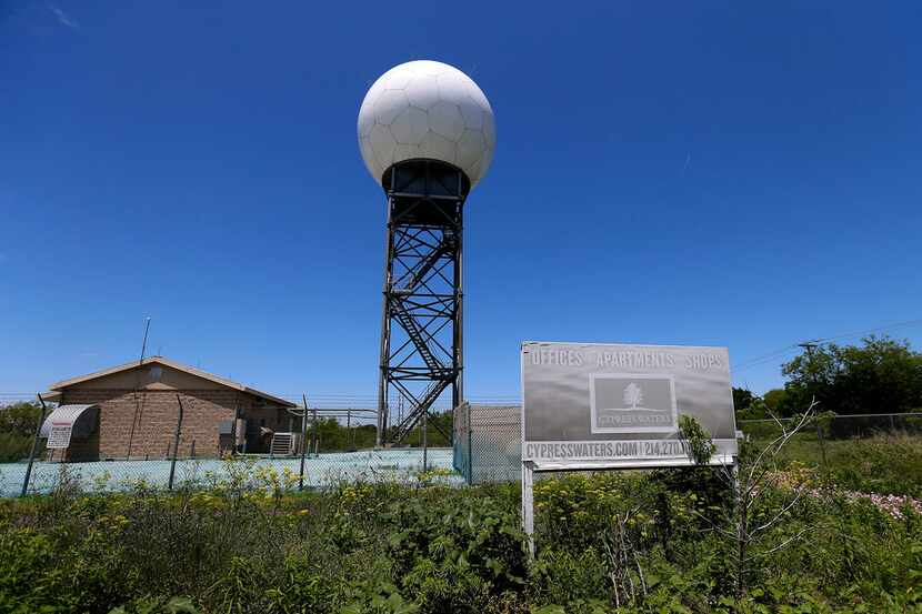 A Cypress Waters development sign sits in front of a Doppler weather radar station used by...