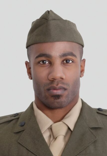 A portrait of a young Black military officer in uniform over a gray background.