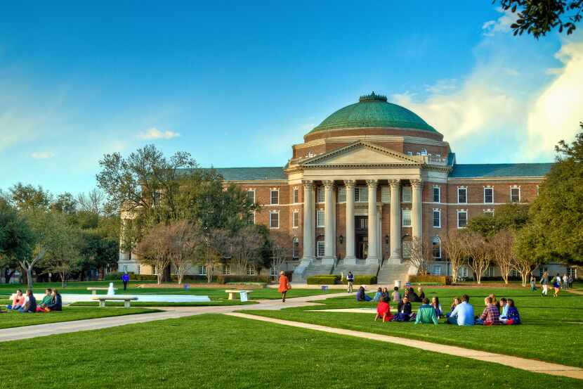 A shot of Dallas Hall at SMU with people sitting on the lawn