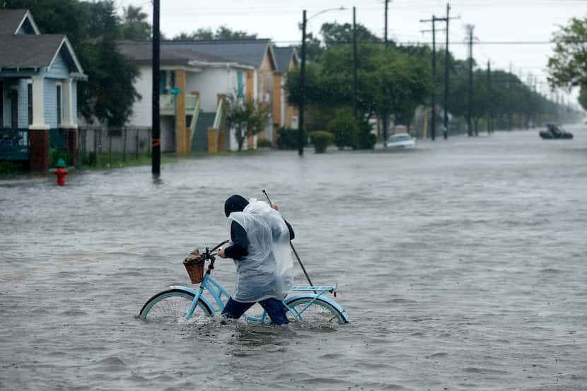 Monica Grant pushes her bike through flooded streets near Broadway Avenue in Galveston on...