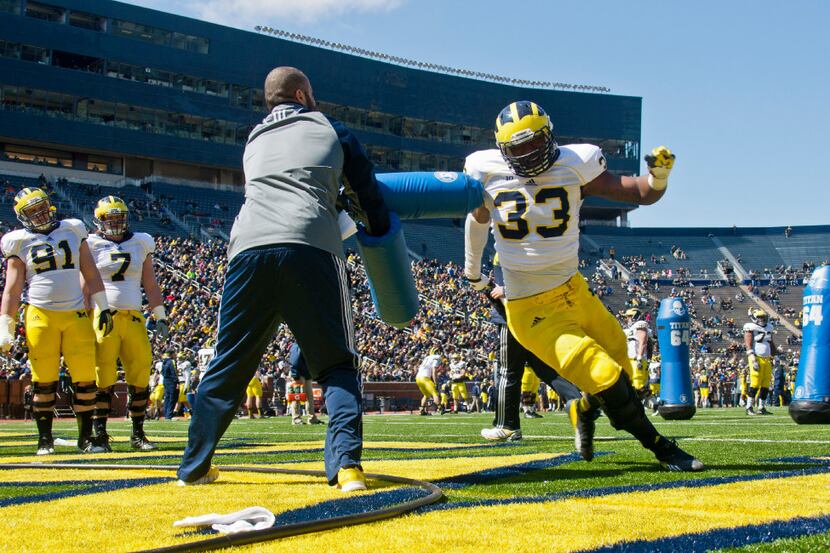 Michigan defensive end Taco Charlton (33) runs around a blocking drill during the football...