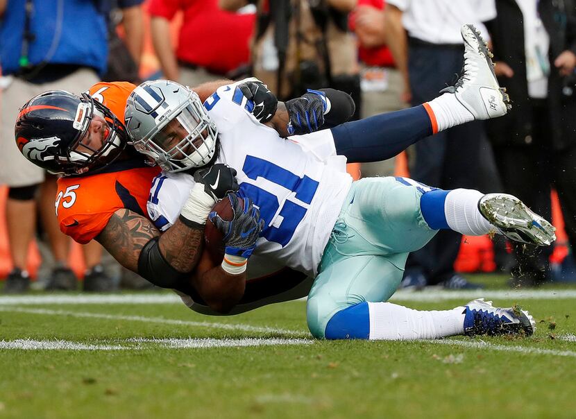 Dallas Cowboys running back Ezekiel Elliott (21) is tackled by Denver Broncos cornerback...