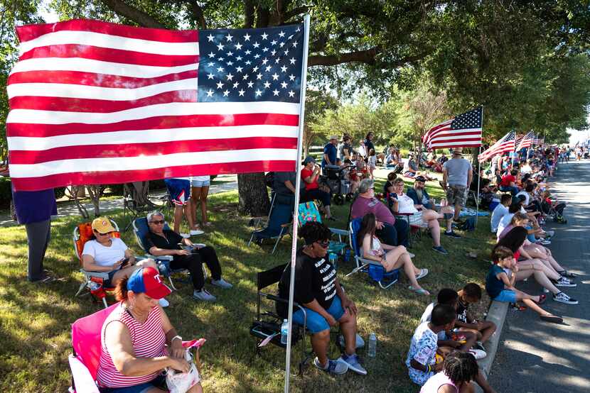 People sit in the shade while watching this year's Independence Day Parade facilitated by...