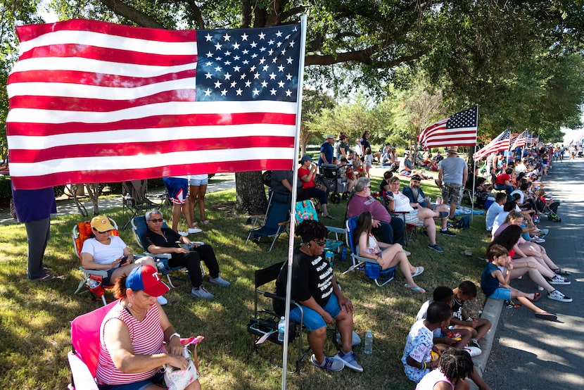 People sit in the shade while watching this year's Independence Day Parade facilitated by...