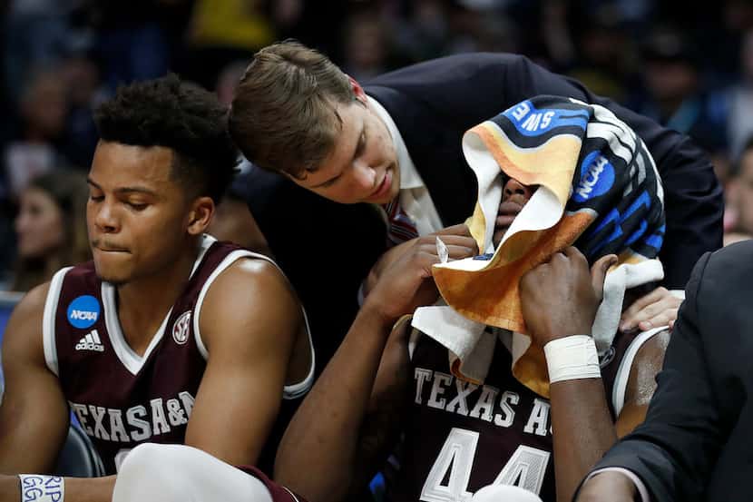 Texas A&M forward Robert Williams, right, covers his face with a towel on the bench during...