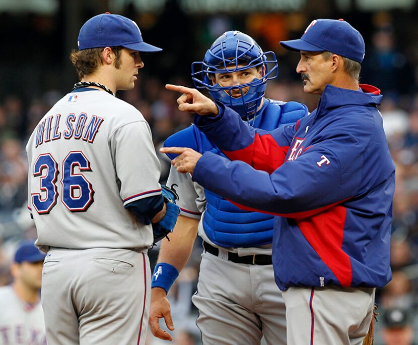  Texas Rangers pitching coach Mike Maddux talks with C.J. Wilson and C Matt Treanor in the...