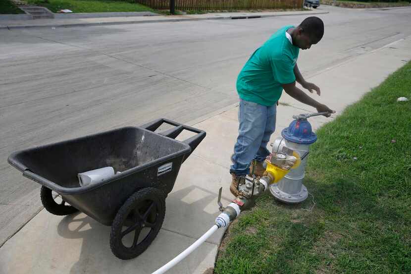 Kebe Cummings  closes a temporary water supply from a fire hydrant that crosses Bexar Street...