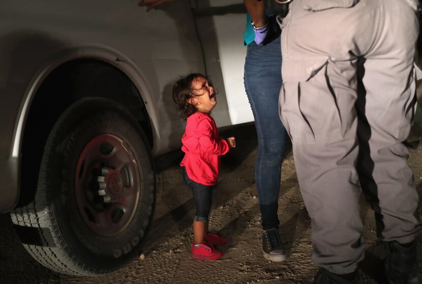   A 2-year-old Honduran asylum seeker cries as her mother is searched and detained near the...