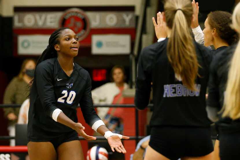 Hebron middle blocker Lia Okammor (20) high-fives teammates after a point during a...