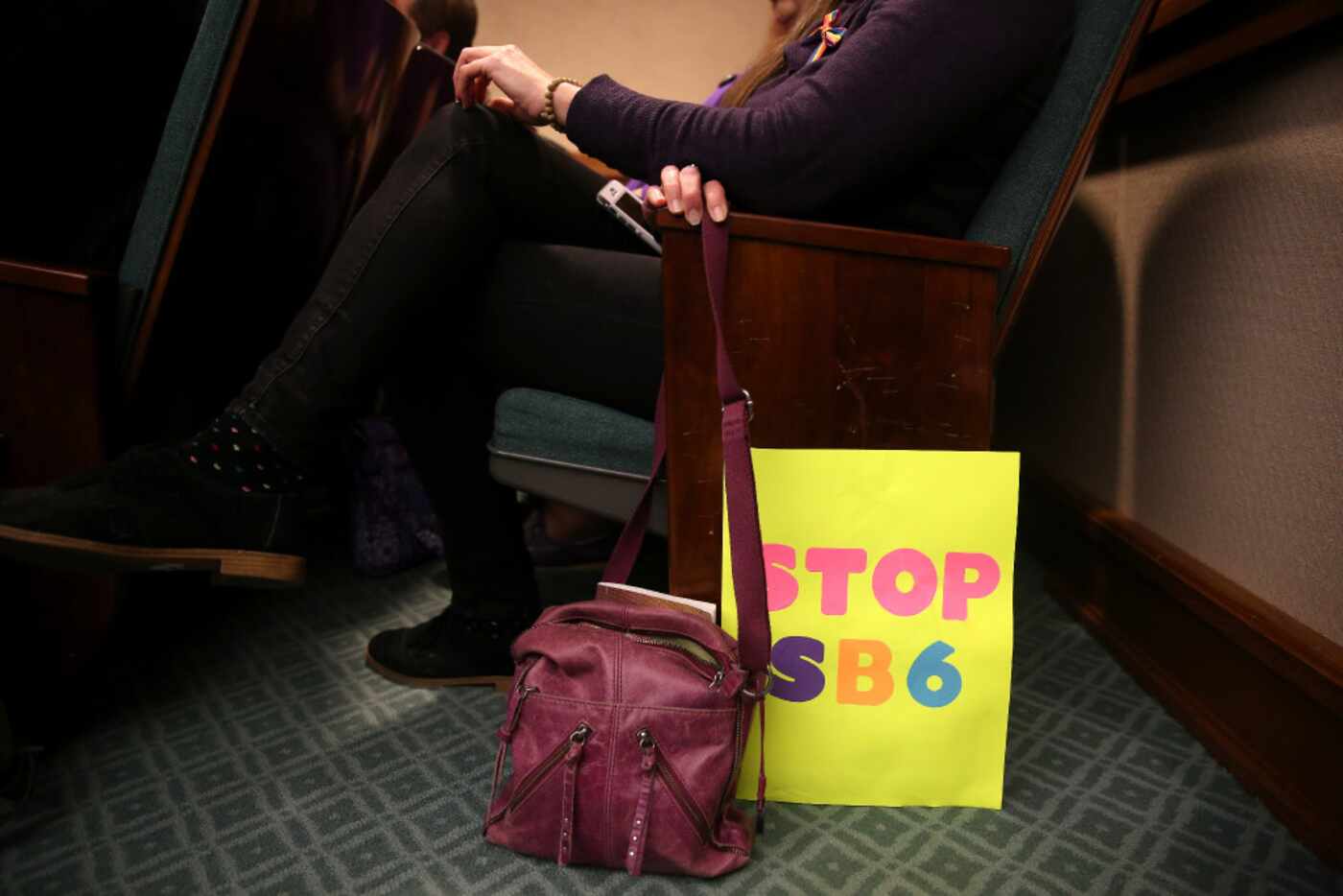 A woman sits with her sign in the overflow room as members of the Senate State Affairs...