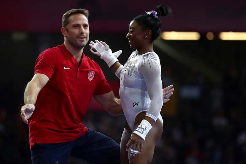 Simone Biles of the U.S. talks to her coach Laurent Landi at the uneven bars during the...