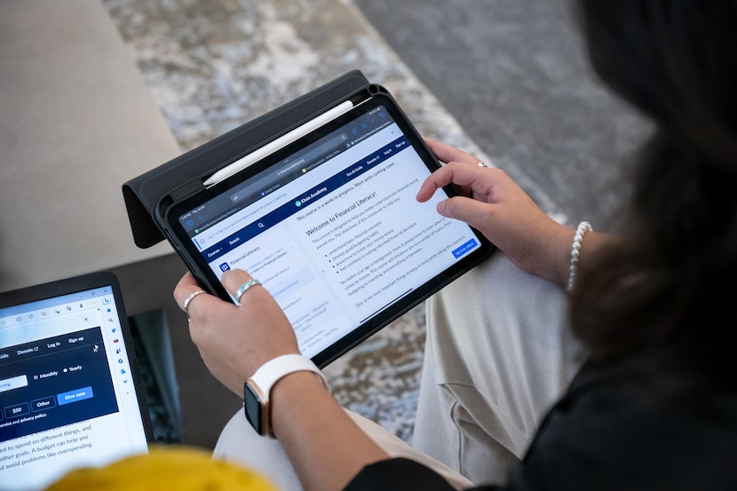 A woman holds an iPad displaying information about auto literacy.