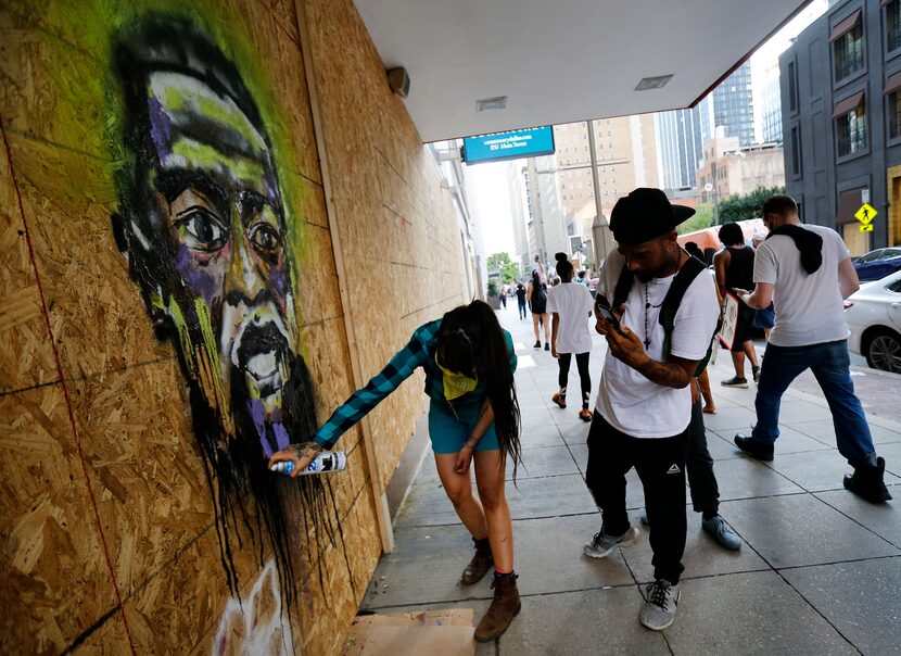 Artist Karla Ceballos spray-paints a portrait of George Floyd on the boarded-up Neiman...