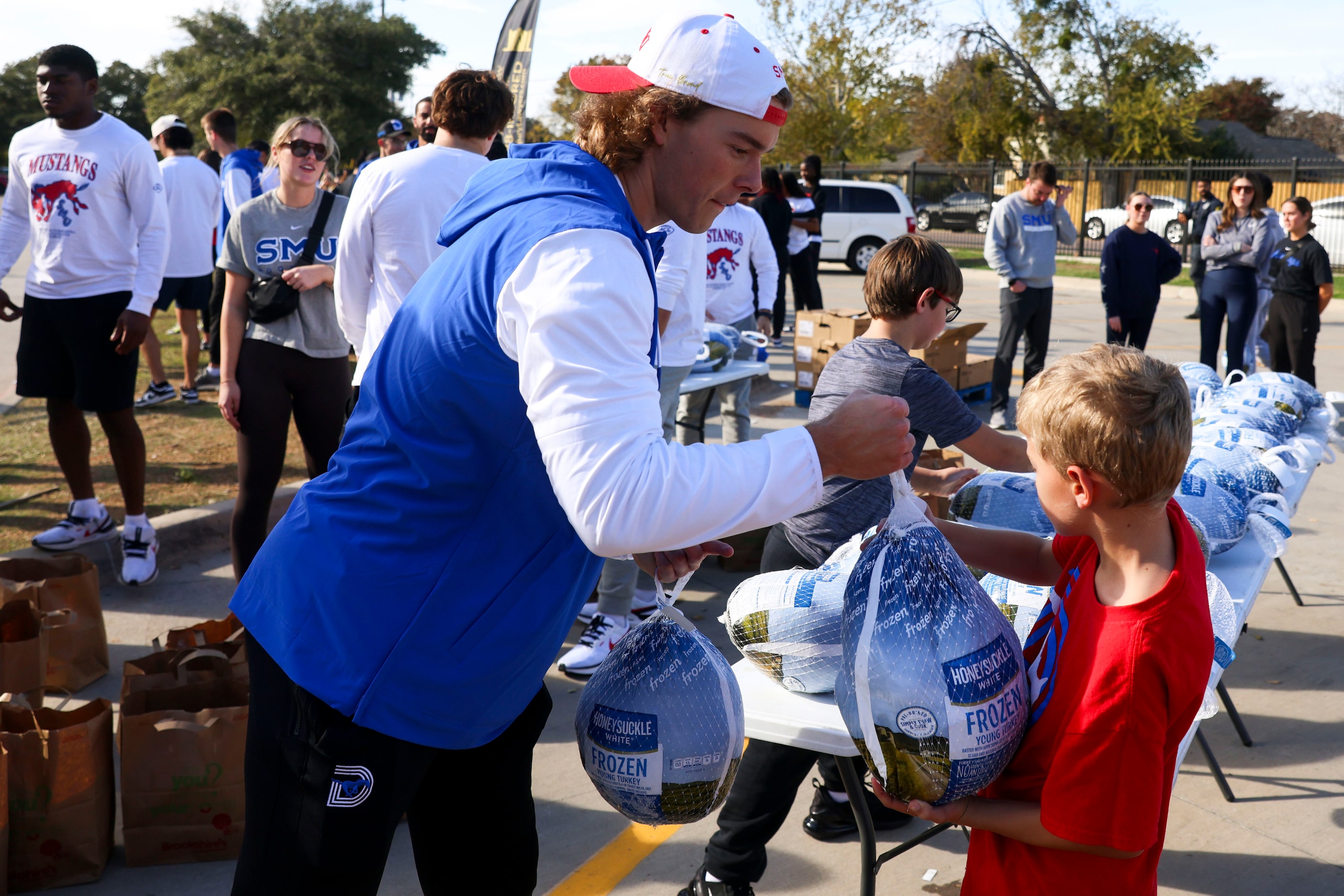 Southern Methodist University’s Maddox Fuller gets turkeys from the side table during a free...