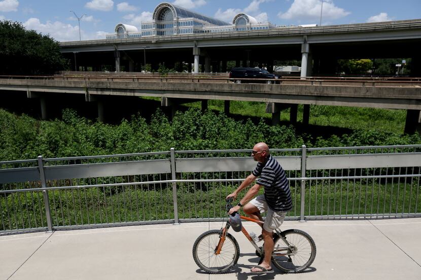 A cyclist rides west along the Trinity Strand Trail's eastern terminus with Interstate 35,...