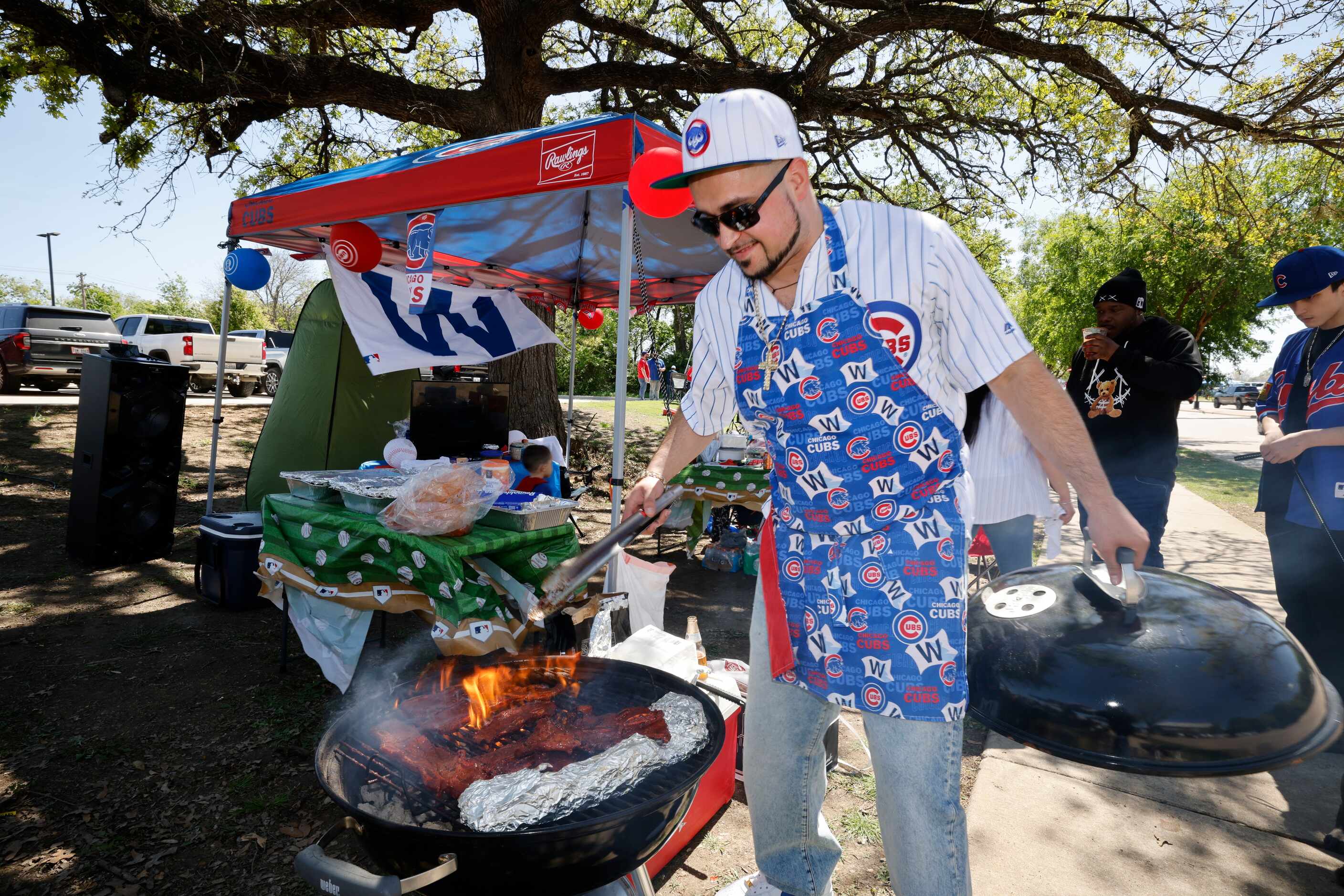 Chicago Cubs fan Adam Lopez of North Dallas cooks while tailgating near Globe Life Field,...