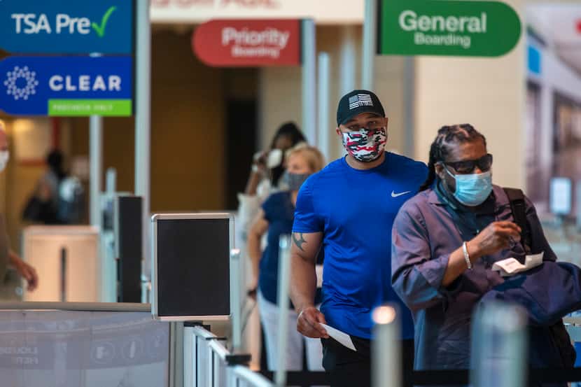 Masked passengers walk to the security checkpoint at Dallas Love Field airport on Sunday,...