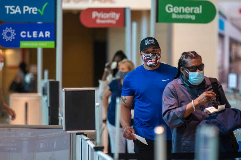 Masked passengers walk to the security checkpoint at Dallas Love Field airport in Dallas on...
