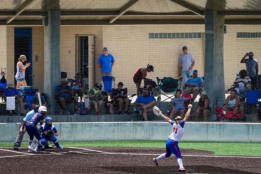 Fans watch a softball game between the Texas Glory 18U team (in white jerseys) and the...