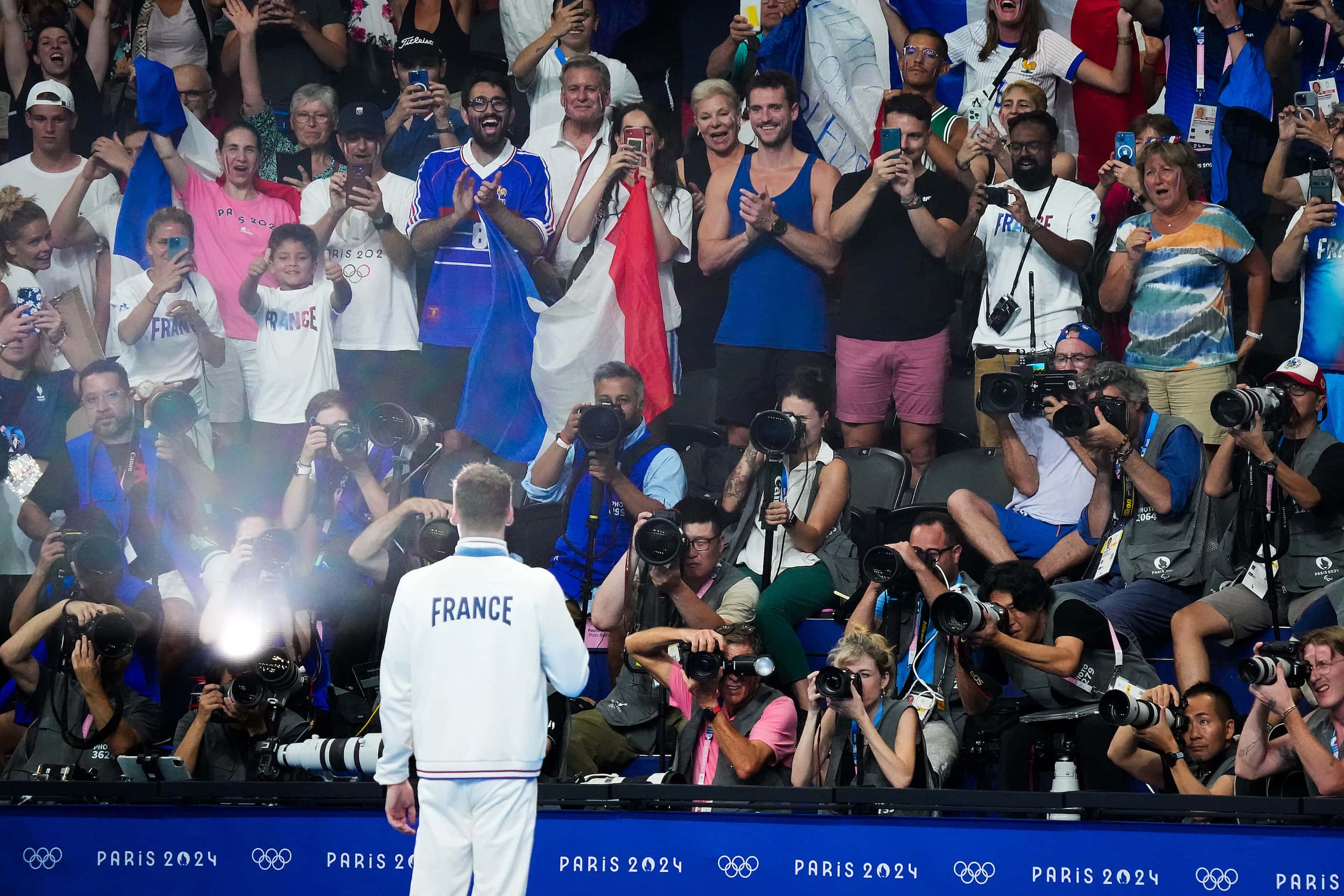 Fans cheer Leon Marchand of France as he poses for photographers with his gold medal after...