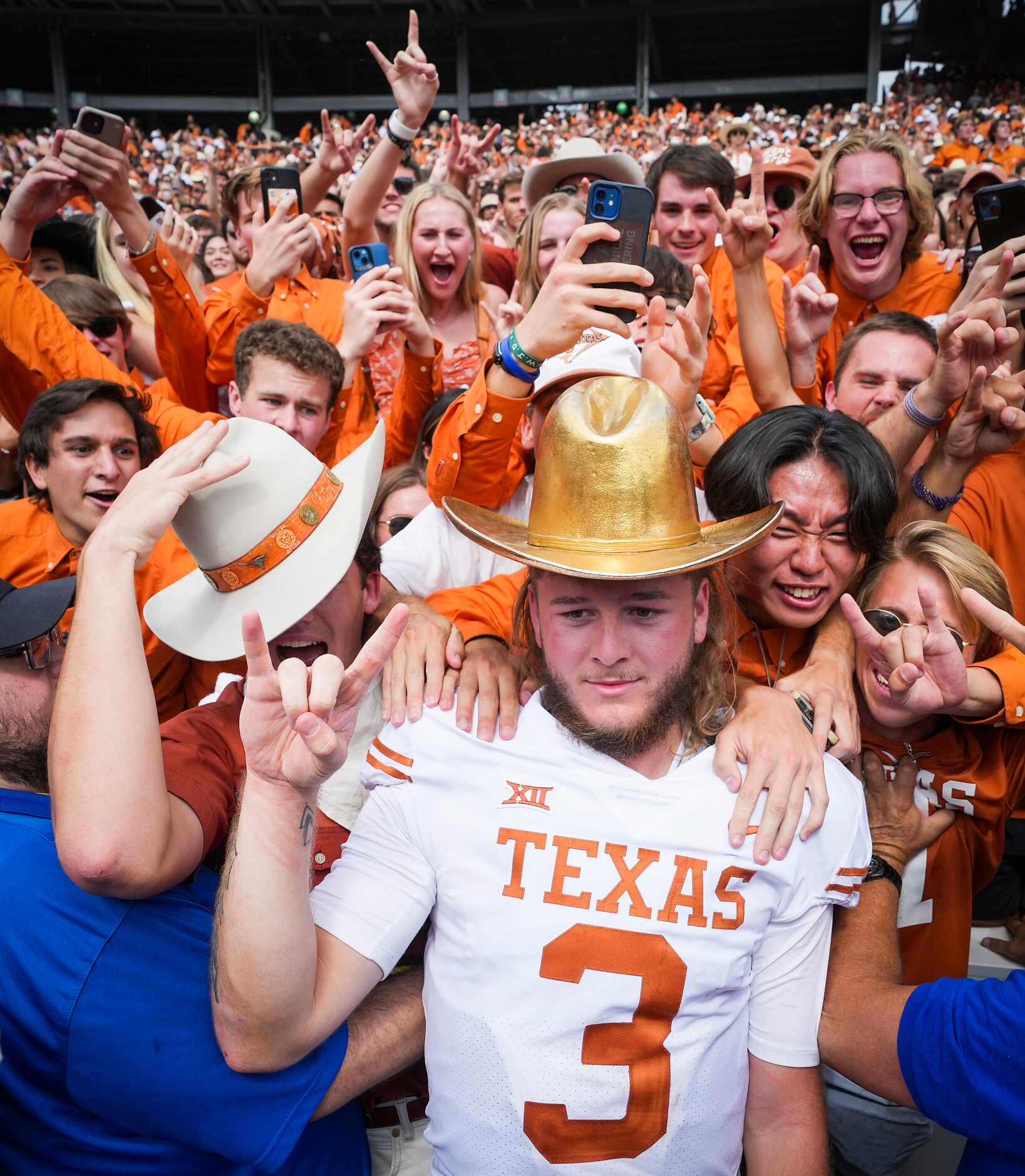 Texas quarterback Quinn Ewers poses wearing the Golden Hat trophy as he celebrates with fans...