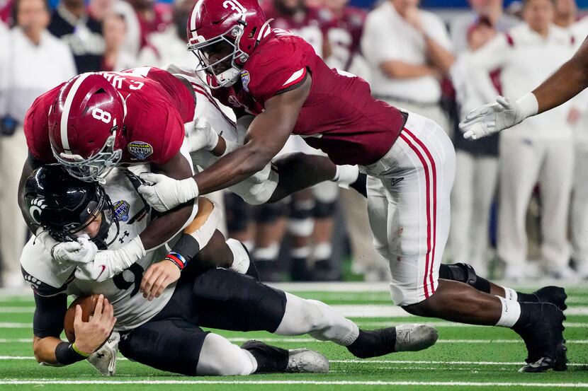 Cincinnati quarterback Desmond Ridder (9) is sacked by Alabama linebacker Christian Harris...