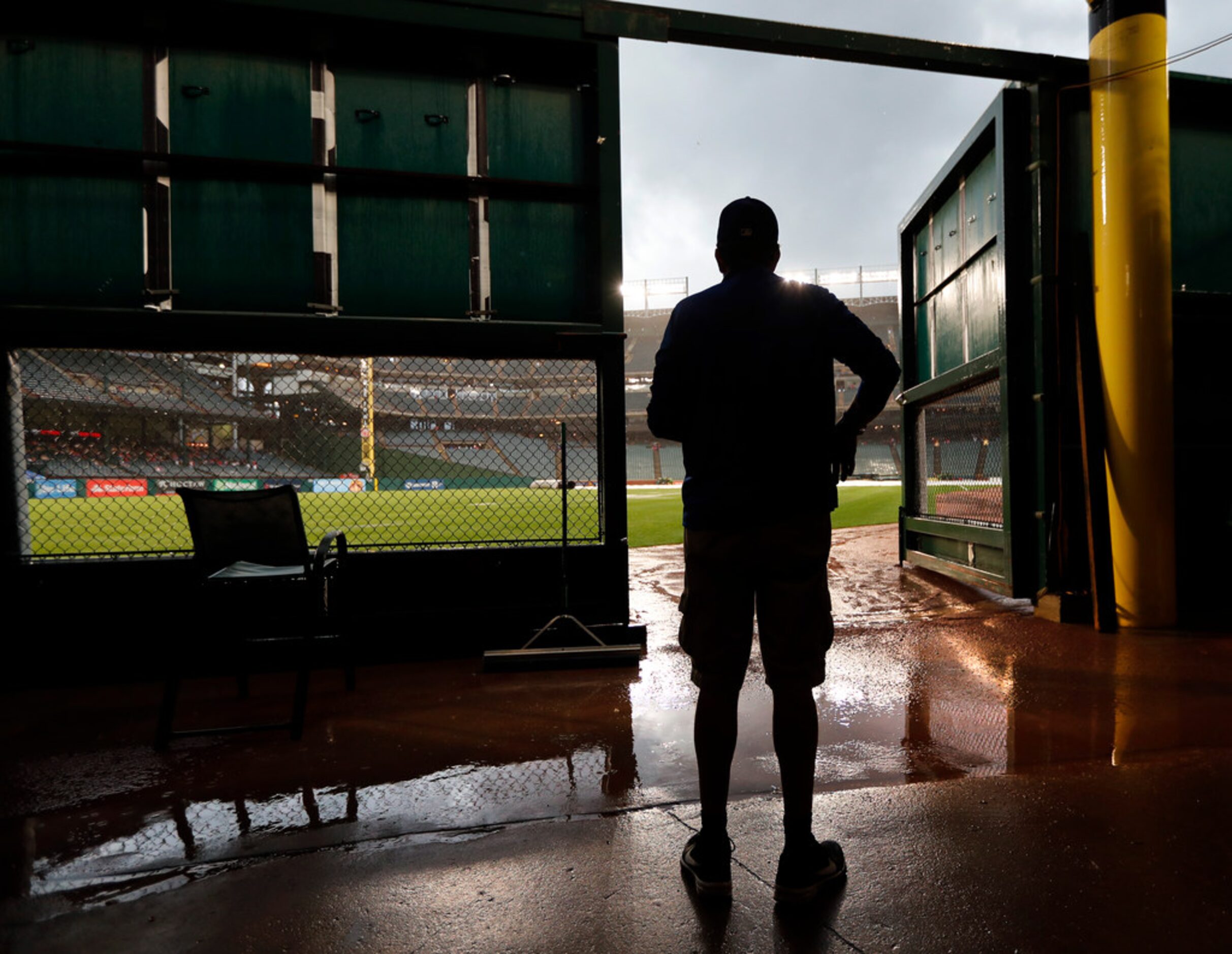 Tracey Rodgers, a Texas Rangers grounds crew member, looks out onto right field as rain...