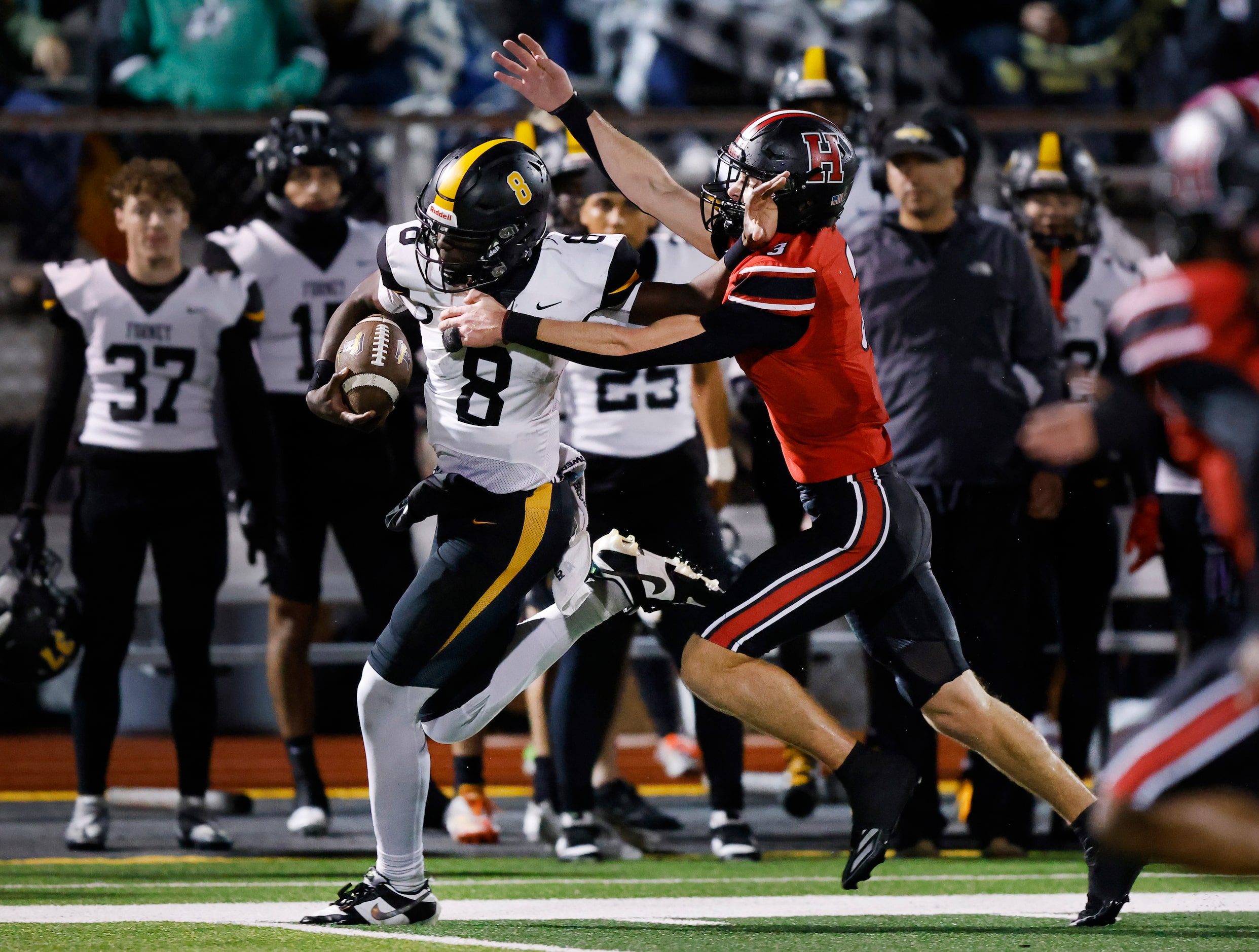 Forney quarterback Nelson Peterson Jr (8) stiff arms Rockwall-Heath safety Dylan McCann (3)...